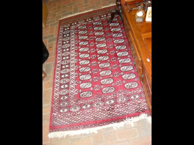 A Middle Eastern burgundy ground rug with triple b