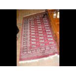 A Middle Eastern burgundy ground rug with triple b