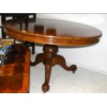 A circular walnut table on carved tripod support -