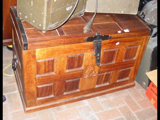 A dome top teak storage trunk with metal handles a