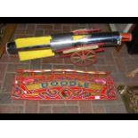 An old painted fairground sign 'Doodle', together with a fairground metal rocket and wagon