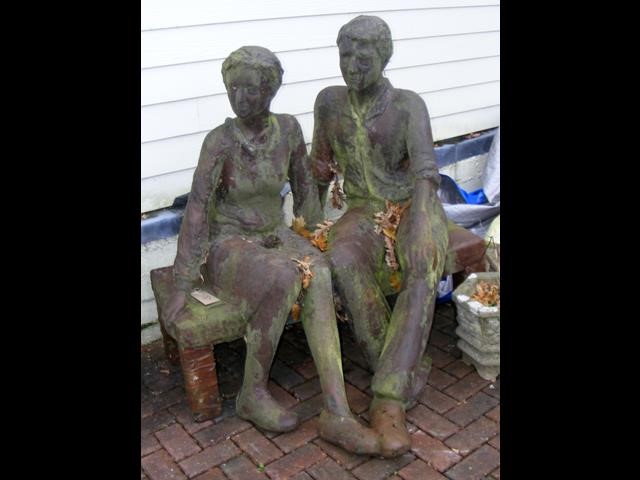 A resign garden ornament of a couple on bench