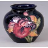 A MOORCROFT SQUAT BULBOUS VASE decorated in a colourful raised slip glaze in the orchid pattern on a