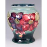 A WALTER MOORCROFT BULBOUS FOOTED VASE decorated in a raised slip glaze with a colourful