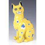 AN EARLY 20th CENTURY GALLE STYLE FAIENCE CAT having a yellow glaze with blue heart decoration and