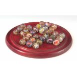 A 19TH CENTURY SOLITAIRE SET WITH OLD CUT PONTIL COLOUR TWIST MARBLES, on a red-stained mahogany