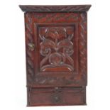 A 17TH CENTURY OAK LANCASHIRE HANGING MURAL CUPBOARD with moulded cornice above a hinged door