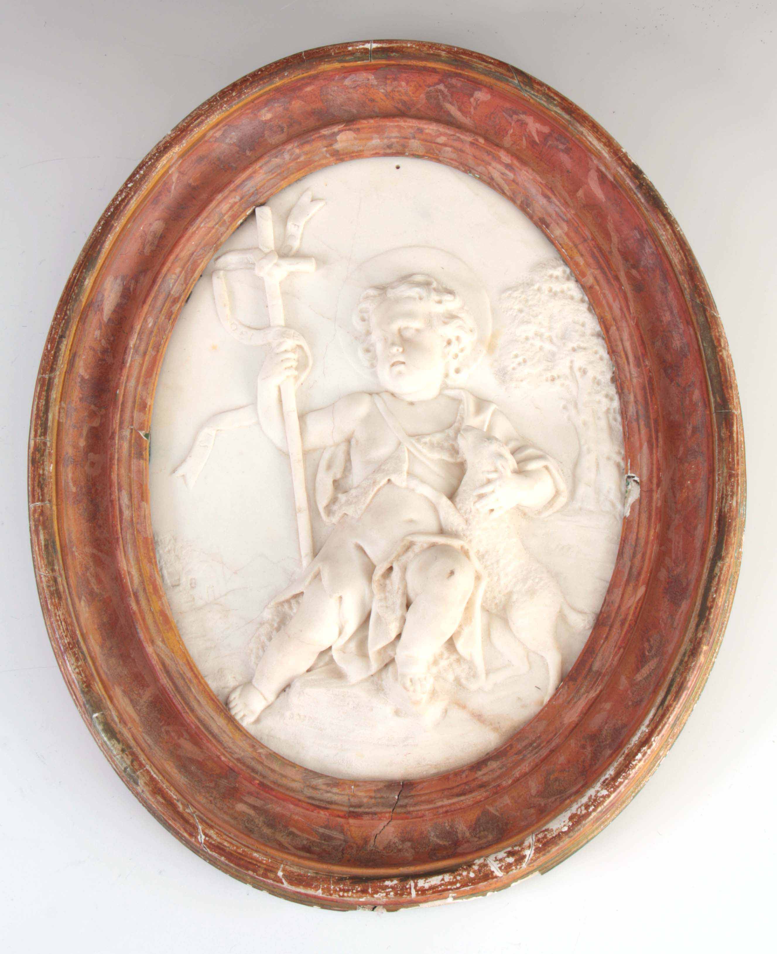 AN 18TH CENTURY OVAL CARVED WHITE MARBLE HANGING WALL PLAQUE depicting a young angel holding a