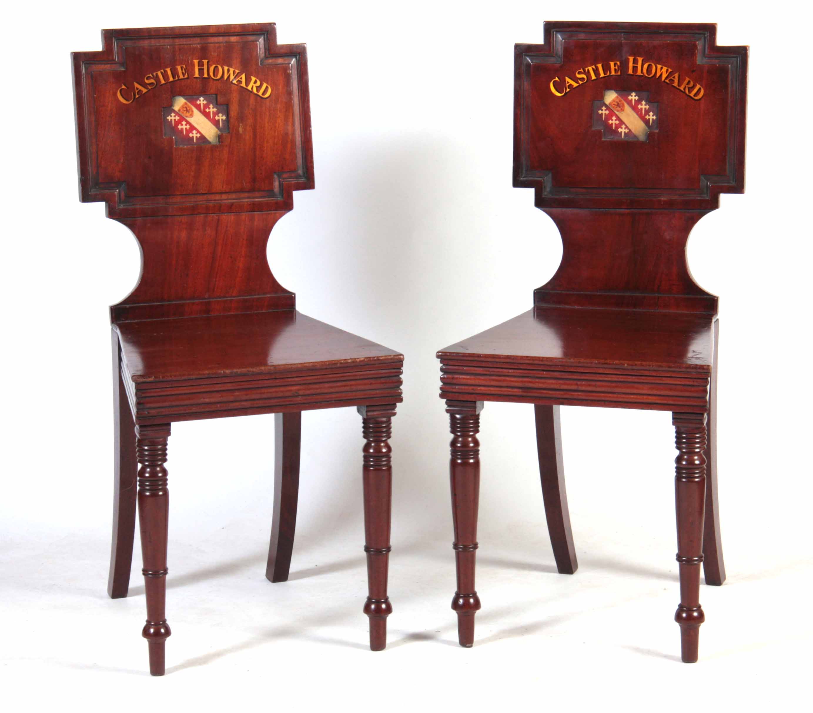 A PAIR OF LATE GEORGIAN MAHOGANY HALL CHAIRS with painted backs reading Castle Howard with coats