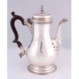 A GEORGE III SILVER COFFEE POT of baluster form on circular foot engraved to one side with a