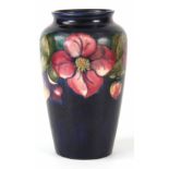 20TH CENTURY WALTER MOORCROFT CLEMATIS PATTERNED VASE on a dark blue ground bearing painted