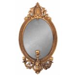 A 19TH CENTURY CARVED AND GILT GESSO GRINENDOLE OVAL HANGING MIRROR with leaf moulded frame and