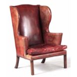 A LATE 19TH CENTURY RED LEATHER WING-BACK ARMCHAIR OF LARGE SIZE having brass studded scrolled