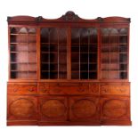 A LATE 18TH CENTURY HEPPLEWHITE FIGURED MAHOGANY BREAKFRONT BOOKCASE the shaped pediment with carved