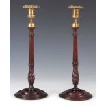 A PAIR OF GEORGE III MAHOGANY CANDLESTICKS with cast brass tops and leaf-work sconces on slender