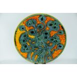 A Poole Pottery Studio charger by Tony Morris depicting multiply seed pods in orange glazed