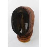 Mid 20thC Leather fencing mask with Mesh front stamped BLG Ltd dated 1949 on walnut stand