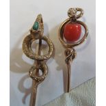A yellow metal stick pin with snake terminal set turquoise and another with snake holding coral