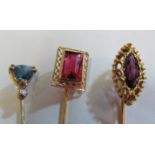 A yellow metal stick pin set amethyst and two other stick pins set coloured stones (i.c.)