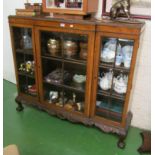 A walnut breakfront display cabinet with three bevelled glass doors on carved frieze with ball and