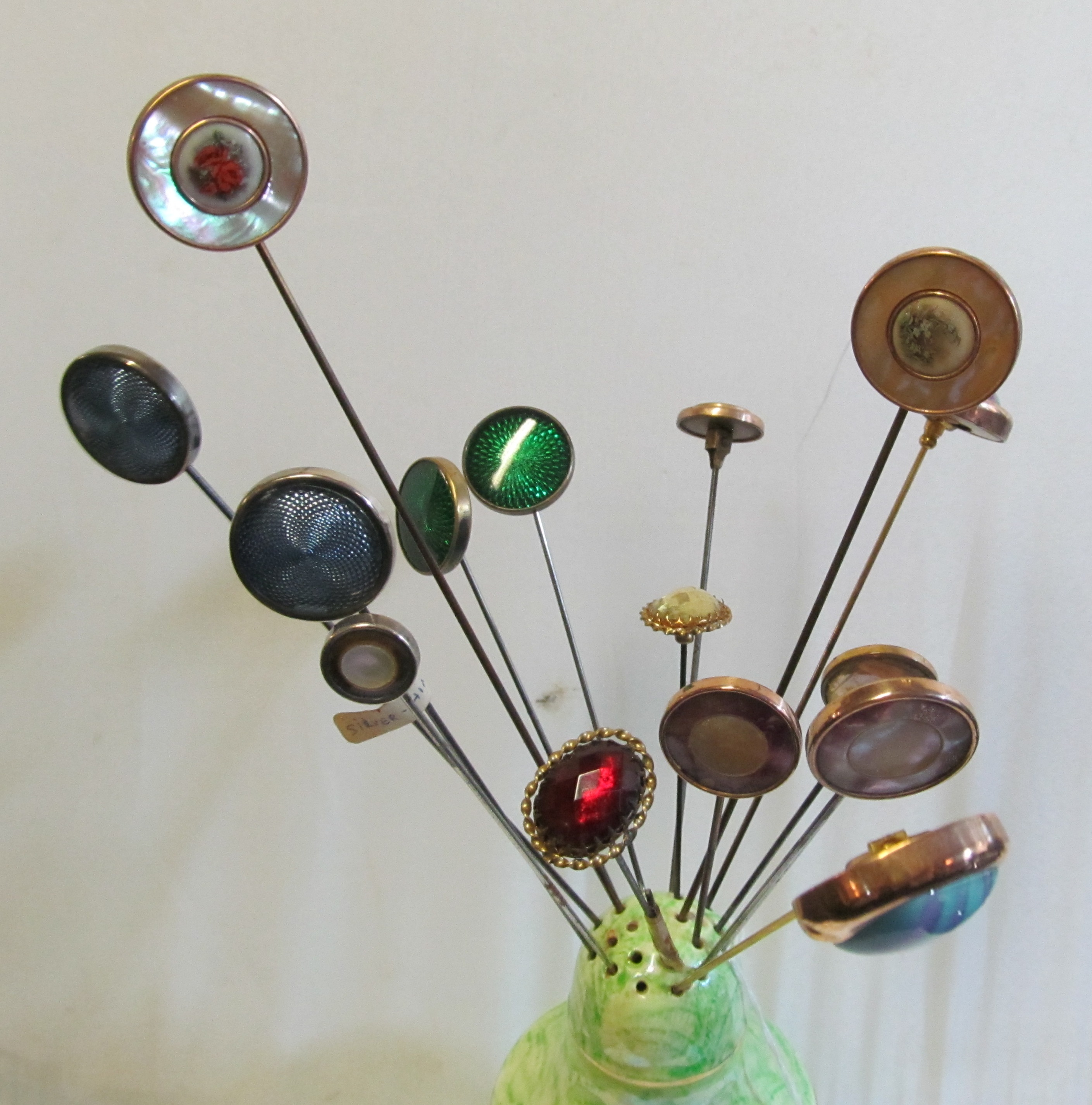 A group of hat pins with button style swivel ends in hat pin holder