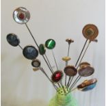 A group of hat pins with button style swivel ends in hat pin holder