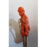 A Victorian stick pin with carved coral terminal of a man with walking stick