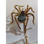 A yellow metal stick pin with spider set garnet and topaz body
