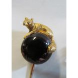 A yellow metal stick pin fox crouching on foil backed red stone