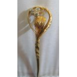 A yellow metal stick pin with diamond flower and leaf design terminal