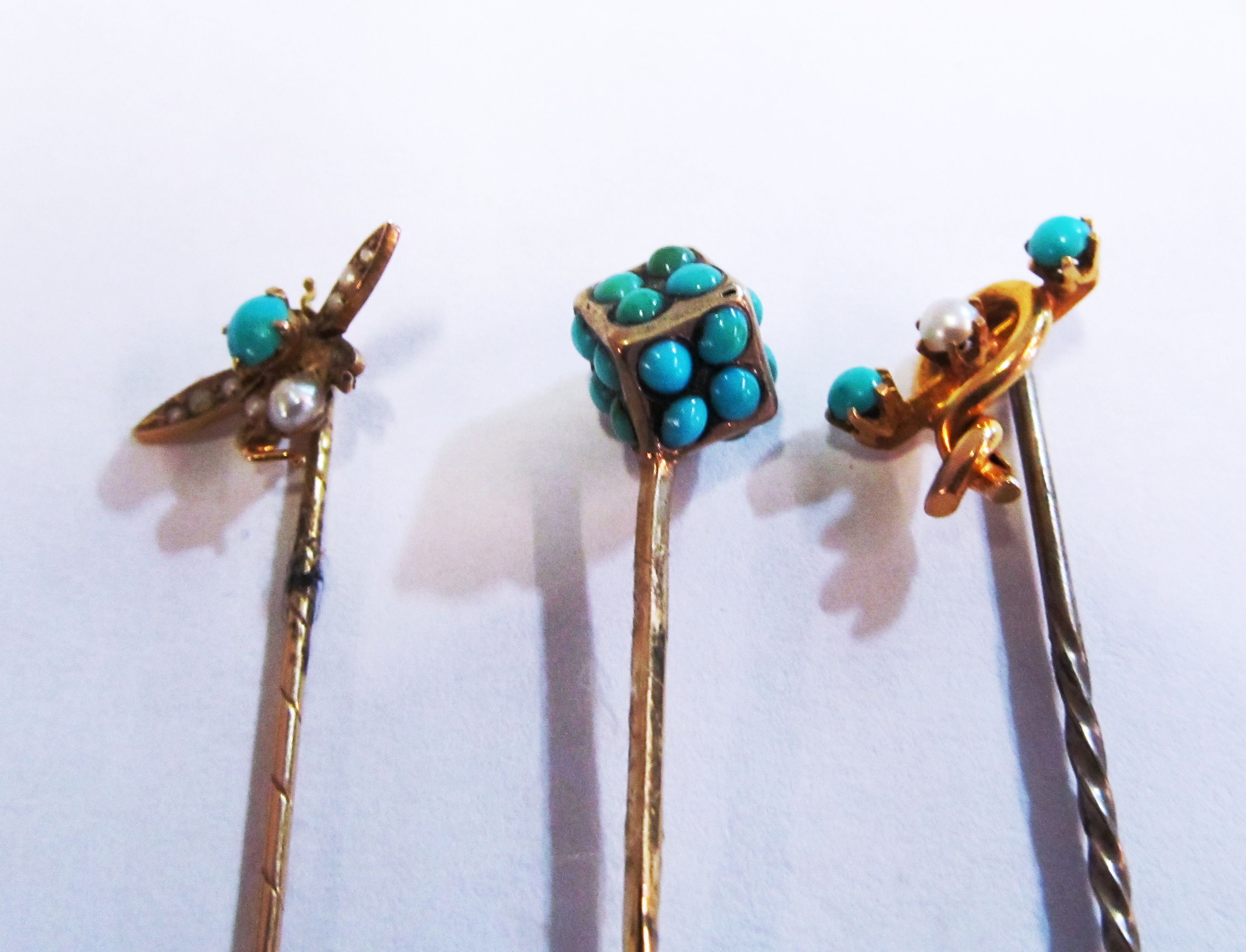 A yellow metal Victorian stick pin with insect terminal set seed pearl and turquoise, another dice