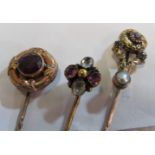 A Victorian amethyst and seed pearl stick pin, another flower head design and another in leaf and