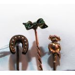 A 9ct gold stick pin Leprechaun, another green enamel bow and another seed pearl and black enamel
