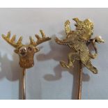 A yellow metal stick pin with stag head terminal and another with lion rampant