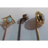 A Victorian mourning stick pin set opal in a black and gilt leaf surround and two other opal stick