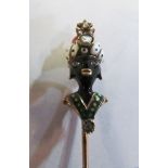 A yellow metal Victorian stick pin set with enamel Blackamore with coral and white stone