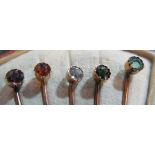 A set of five yellow metal stick pins set ruby, garnet, diamond, sapphire and emerald in fan
