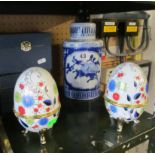 A blue lidded vase and two boxed eggs.