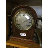 A 1920's oak mantel clock with barley twist side pillars and silver dial