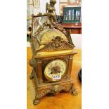 A square brass mantel clock with cherub top and enamel dial