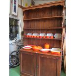 A 1920s oak dresser with three tier plate rack and cupboard under