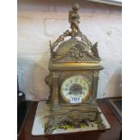 A square brass mantel clock with cherub top and enamel dial