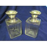 A pair of glass scent bottles with French white metal stoppers