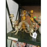 A pair of winged Griffin candlesticks and a pair of gilt cherub candlesticks.