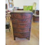 A bow fronted tall chest of five drawers