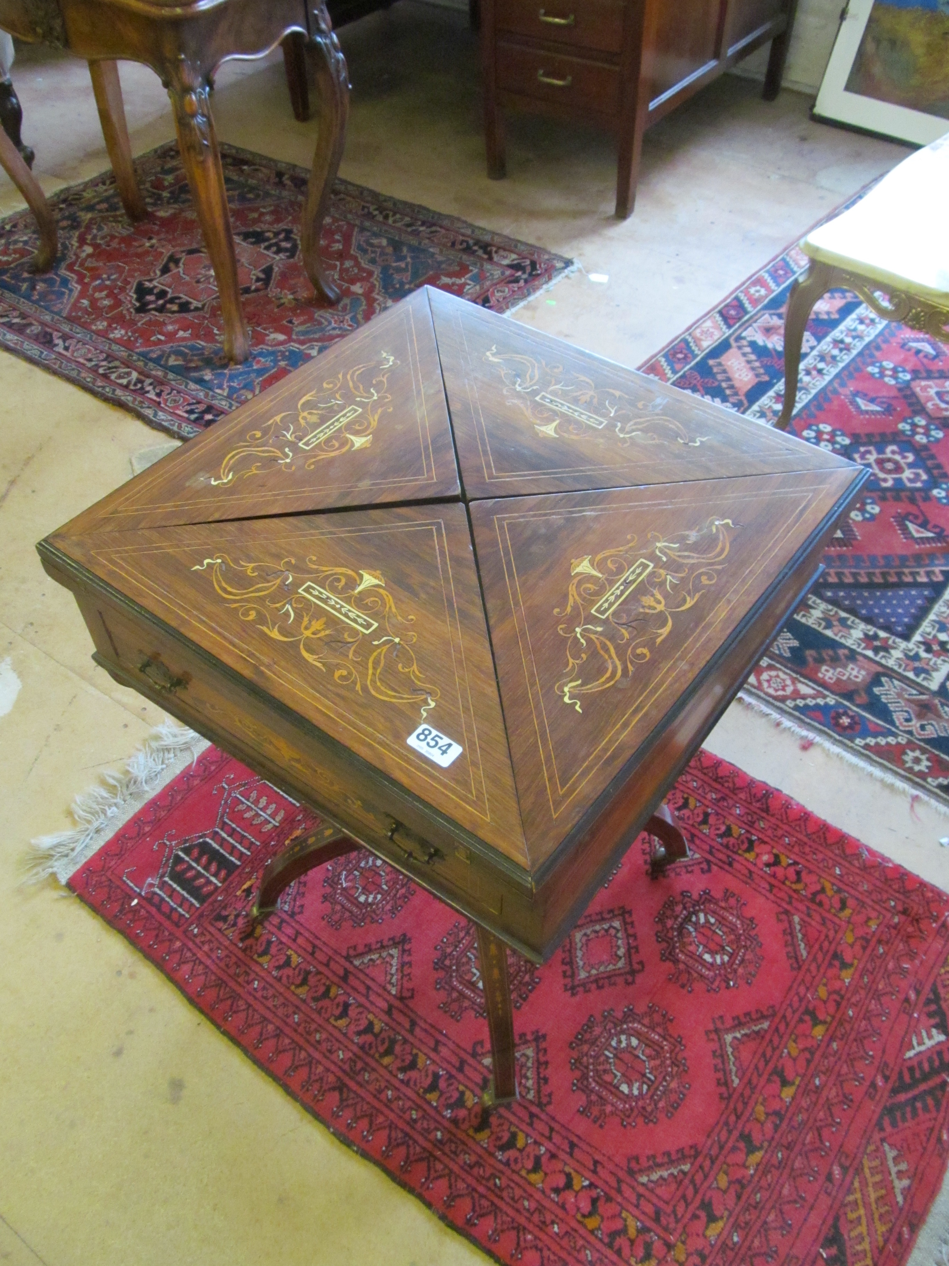 A late Victorian rosewood and inlaid envelope card table with drawer on shaped supports round a