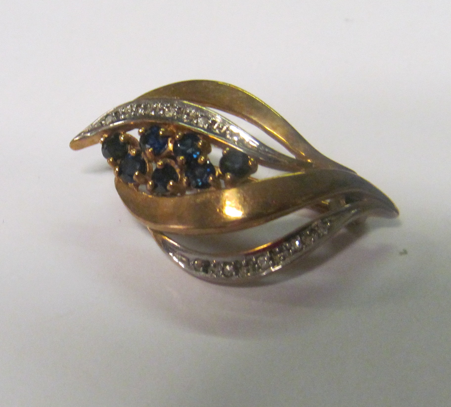 A 9ct gold diamond and sapphire brooch in the form of a leafed bud with seven dark blue square cut