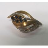 A 9ct gold diamond and sapphire brooch in the form of a leafed bud with seven dark blue square cut