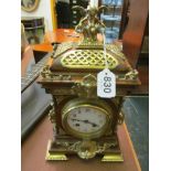 A rosewood effect mantel clock with cherub finial, white enamel dial, eight day striking movement