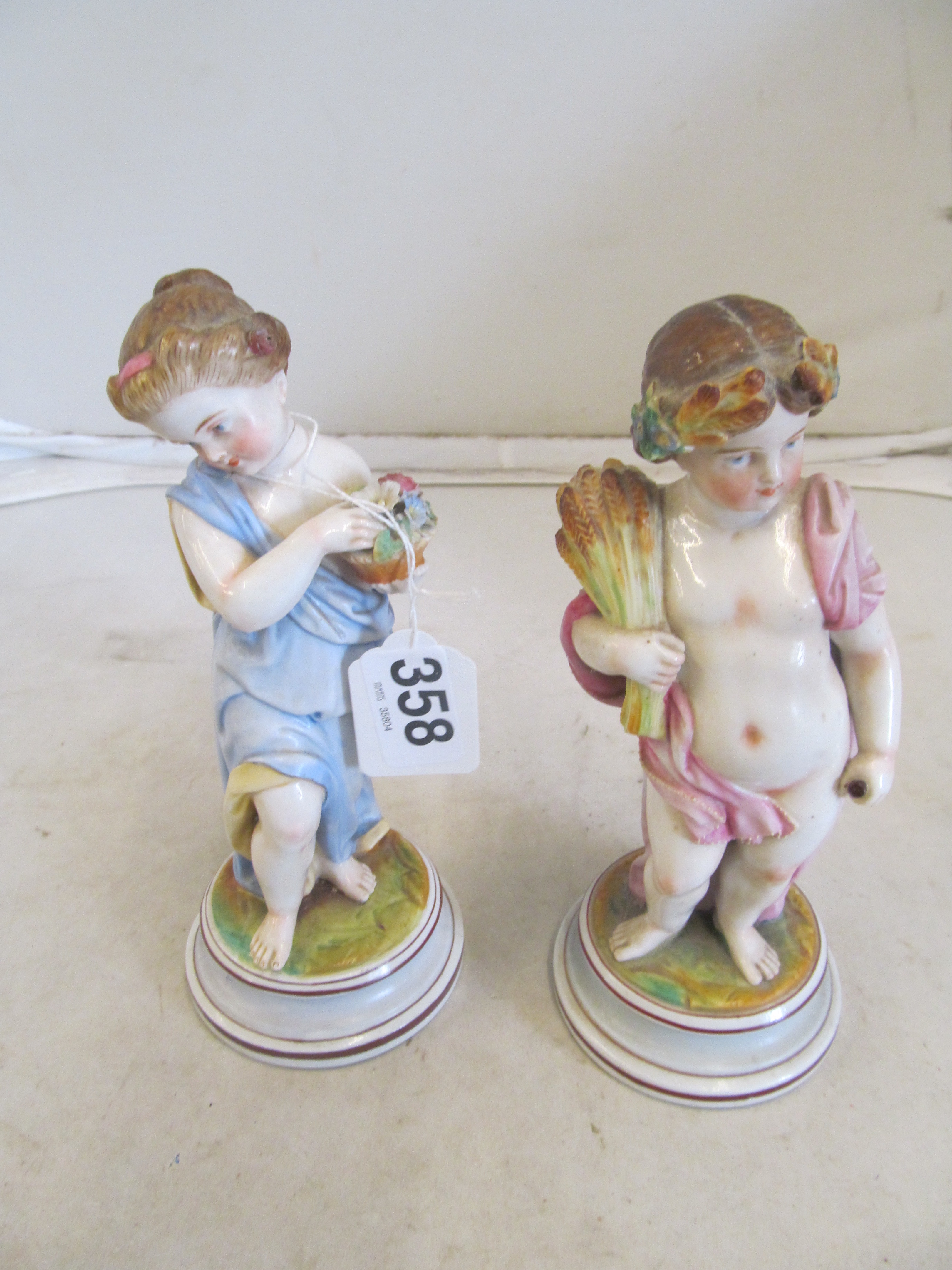 A pair of porcelain figures cherubs spring and autumn (1 a/f) on circular bases and a Coalport plate
